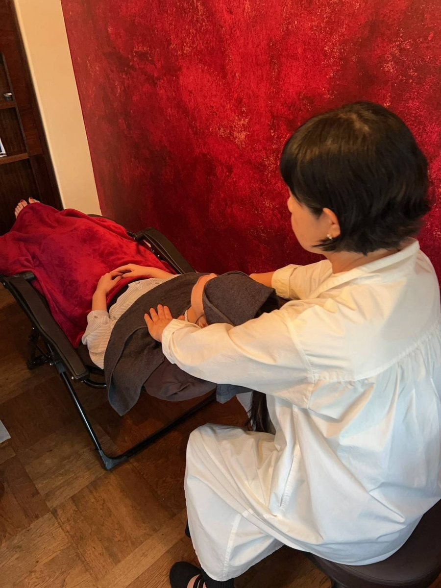 リクライニングチェアに横になったお客さまの頭を、施術者が手でほぐしている様子